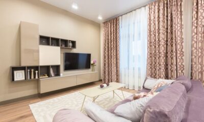 Modern small living room color ideas showing warm beige walls paired with a mauve sofa and patterned curtains