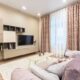 Modern small living room color ideas showing warm beige walls paired with a mauve sofa and patterned curtains
