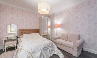 Pink damask bedroom with tufted headboard, blush sofa, and mirrored vanity