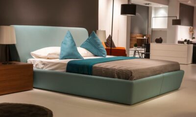 Teal upholstered bed frame with matching throw pillows and walnut nightstand in a modern bedroom showroom